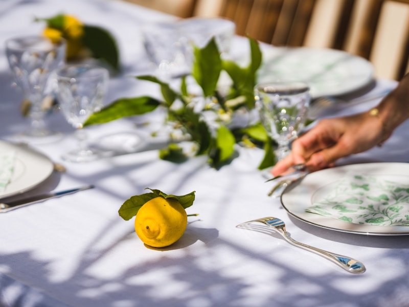 A gardener's hands collecting ripe tomato seeds on a glass plate with sunlight in the background