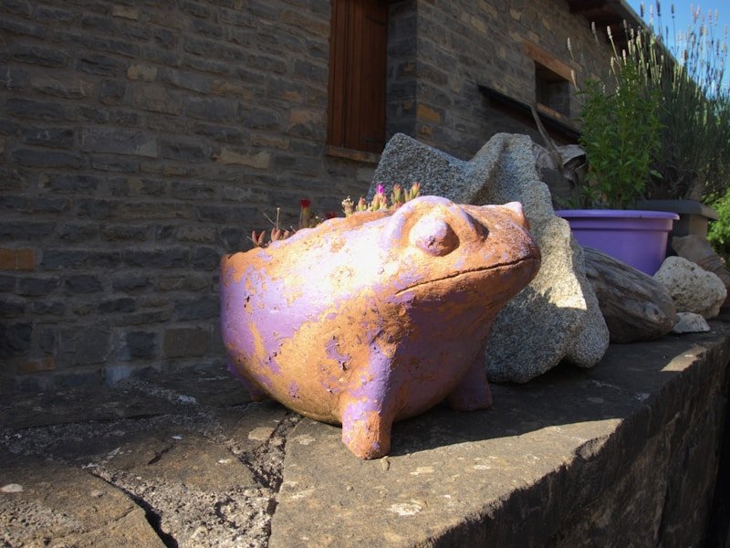 Person measuring a large terracotta pot on a sunny patio for growing vegetables