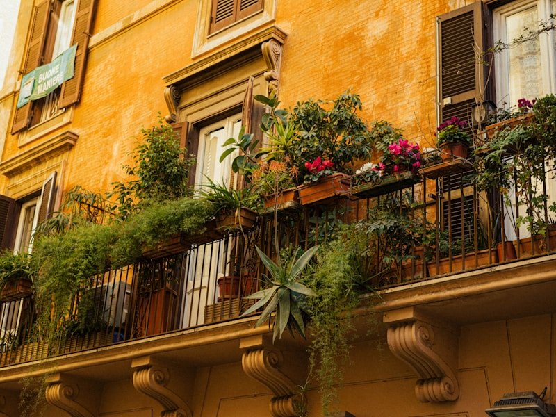 Vertical herb garden system installed on a small balcony with multiple tiers of basil and mint