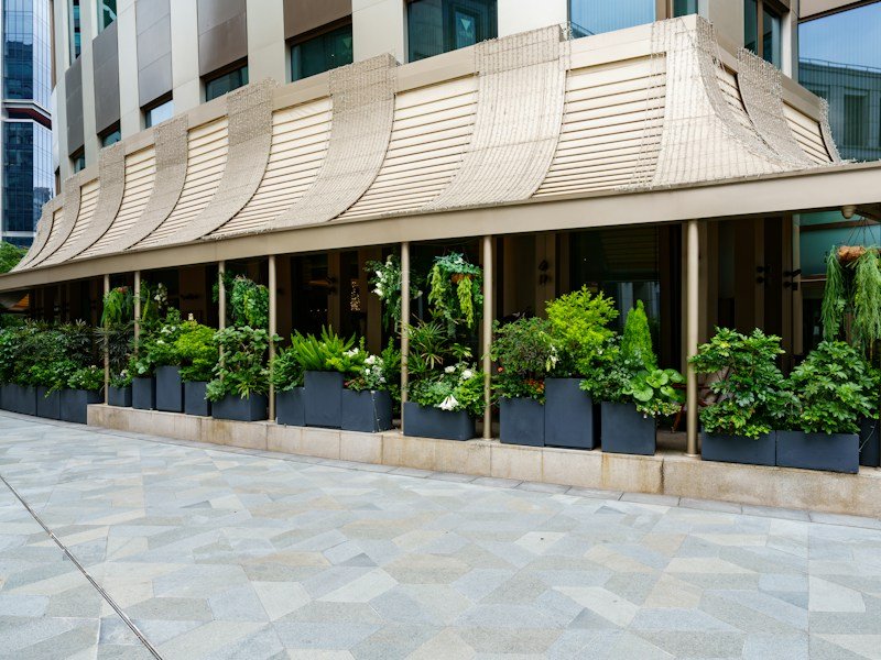 Landscape crew installing self-watering planters and drip irrigation on a compact commercial patio
