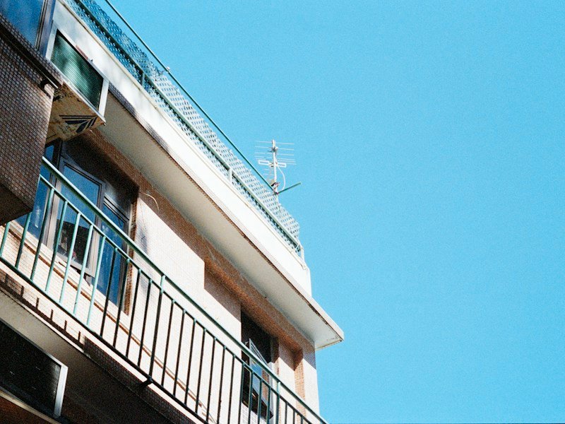 Videographer filming a balcony drip irrigation installation with an overhead camera rig on an urban apartment balcony