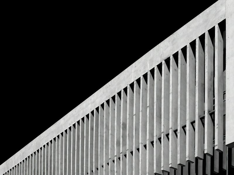Installer torquing stainless steel anchor bolts securing an aluminum louvered wind screen to a concrete balcony slab edge